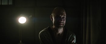 Movie still from “Suicide Squad” (2016), directed by David Ayer – A man with a bald head is looking at the camera; Close Up shot, Low angle