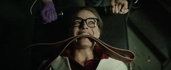 Movie still from “Suicide Squad” (2016), directed by David Ayer – A woman with glasses is holding a pair of shoes in front of her face; Close Up shot, Over the shoulder angle