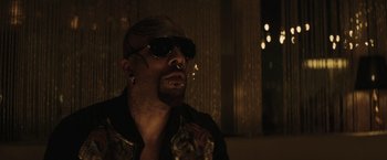 Movie still from “Suicide Squad” (2016), directed by David Ayer – A person wearing sunglasses and a jacket; Close Up shot, Low angle