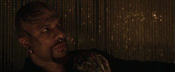 Movie still from “Suicide Squad” (2016), directed by David Ayer – A person with tattoos on their face; Close Up shot, Over the shoulder angle