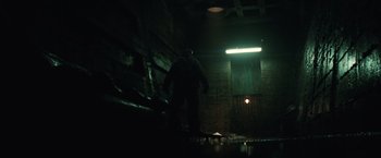 Movie still from “Suicide Squad” (2016), directed by David Ayer – A man standing in a dark room next to a door; Wide shot, Low angle