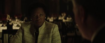 Movie still from “Suicide Squad” (2016), directed by David Ayer – A woman sitting in front of a group of people in a room; Close Up shot, Over the shoulder angle