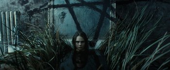 Movie still from “Suicide Squad” (2016), directed by David Ayer – A woman is sitting in the water in front of a window; Medium shot, Overhead angle