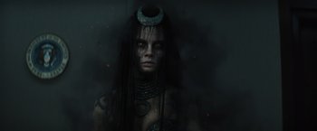 Movie still from “Suicide Squad” (2016), directed by David Ayer – A woman with long black hair wearing a green and blue headpiece; Close Up shot, High angle