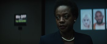 Movie still from “Suicide Squad” (2016), directed by David Ayer – A woman in a suit and pearl necklace looking to her left; Close Up shot, Over the shoulder angle