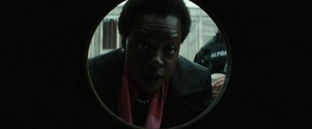 Movie still from “Suicide Squad” (2016), directed by David Ayer – A woman looking into a round mirror in a room; Close Up shot, Over the shoulder angle