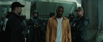 Movie still from “Suicide Squad” (2016), directed by David Ayer – A group of men standing next to each other in front of a tent; Medium shot, Low angle