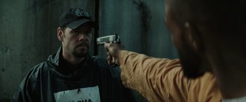 Movie still from “Suicide Squad” (2016), directed by David Ayer – A man holding a gun pointed at another man's reflection in a mirror; Close Up shot, Over the shoulder angle