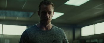 Movie still from “Suicide Squad” (2016), directed by David Ayer – A person wearing a gray t - shirt; Close Up shot, Low angle