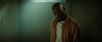 Movie still from “Suicide Squad” (2016), directed by David Ayer – A man with a beard is standing in a dark room; Close Up shot, Low angle