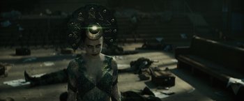 Movie still from “Suicide Squad” (2016), directed by David Ayer – A woman in a green and black costume with a black headpiece; Medium shot, Over the shoulder angle