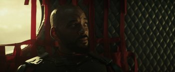 Movie still from “Suicide Squad” (2016), directed by David Ayer – A man with a beard is looking into the distance; Close Up shot, Over the shoulder angle