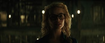 Movie still from “Suicide Squad” (2016), directed by David Ayer – A woman with blonde curly hair wearing glasses; Close Up shot, Low angle