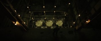 Movie still from “Suicide Squad” (2016), directed by David Ayer – A man standing in front of a large machine room; Extreme Wide shot, Overhead angle