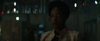 Movie still from “Suicide Squad” (2016), directed by David Ayer – A black woman with short black hair wearing a jacket and pearls; Close Up shot, Low angle