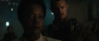 Movie still from “Suicide Squad” (2016), directed by David Ayer – A man and a woman are standing in a dark room; Close Up shot, Over the shoulder angle