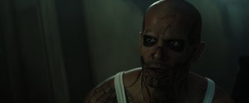 Movie still from “Suicide Squad” (2016), directed by David Ayer – A person with tattoos on their face; Close Up shot, Over the shoulder angle