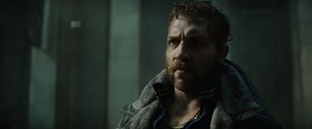 Movie still from “Suicide Squad” (2016), directed by David Ayer – A man with a beard is looking at the camera; Close Up shot, Low angle