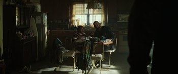 Movie still from “Suicide Squad” (2016), directed by David Ayer – A man and a woman sitting at a table in a kitchen; Medium shot, High angle
