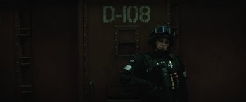 Movie still from “Suicide Squad” (2016), directed by David Ayer – A man in a black suit and helmet standing in front of a door; Medium shot, Low angle