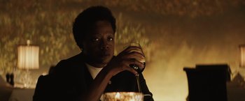 Movie still from “Suicide Squad” (2016), directed by David Ayer – A woman holding a wine glass in a dimly - lit room; Close Up shot, Low angle