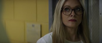 Movie still from “Suitable Flesh” (2023), directed by Joe Lynch – A woman wearing glasses and a white shirt looking to her left; Close Up shot, Over the shoulder angle