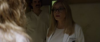 Movie still from “Suitable Flesh” (2023), directed by Joe Lynch – A woman wearing glasses and a white jacket; Close Up shot, Over the shoulder angle