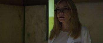 Movie still from “Suitable Flesh” (2023), directed by Joe Lynch – A woman wearing glasses and a white shirt; Close Up shot, Low angle