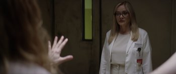 Movie still from “Suitable Flesh” (2023), directed by Joe Lynch – A woman in a white suit and a man in a white suit; Medium shot, Over the shoulder angle