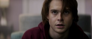 Movie still from “Suitable Flesh” (2023), directed by Joe Lynch – A person with long brown hair; Close Up shot, Over the shoulder angle