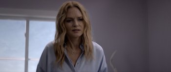 Movie still from “Suitable Flesh” (2023), directed by Joe Lynch – A woman with long blonde hair is wearing a blue shirt; Close Up shot, Over the shoulder angle