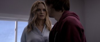 Movie still from “Suitable Flesh” (2023), directed by Joe Lynch – A woman standing next to a man in a room; Close Up shot, Over the shoulder angle