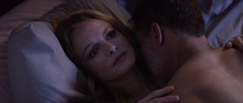 Movie still from “Suitable Flesh” (2023), directed by Joe Lynch – A person laying in a bed with another person; Close Up shot, Over the shoulder angle