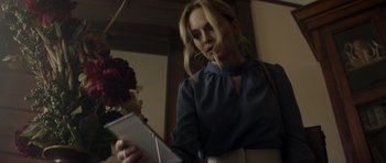 Movie still from “Suitable Flesh” (2023), directed by Joe Lynch – A woman is looking at her cell phone; Medium shot, Low angle