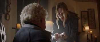 Movie still from “Suitable Flesh” (2023), directed by Joe Lynch – A woman looking at an older woman with a pen in her hand; Medium shot, Over the shoulder angle