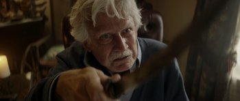 Movie still from “Suitable Flesh” (2023), directed by Joe Lynch – An older man holding a knife in his hand; Close Up shot, Over the shoulder angle