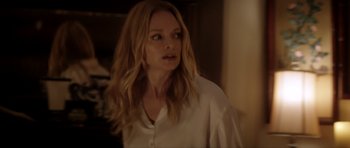 Movie still from “Suitable Flesh” (2023), directed by Joe Lynch – A woman in a white shirt is standing in a room; Close Up shot, Over the shoulder angle