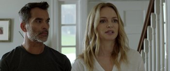 Movie still from “Suitable Flesh” (2023), directed by Joe Lynch – A woman standing next to a man in front of a window; Close Up shot, Over the shoulder angle