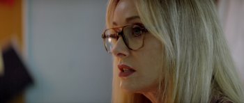 Movie still from “Suitable Flesh” (2023), directed by Joe Lynch – A person wearing glasses and looking to the side; Close Up shot, Over the shoulder angle