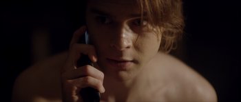 Movie still from “Suitable Flesh” (2023), directed by Joe Lynch – A young man talking on a cell phone; Close Up shot, Low angle