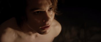 Movie still from “Suitable Flesh” (2023), directed by Joe Lynch – A young man's face in the dark; Close Up shot, Over the shoulder angle