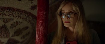 Movie still from “Suitable Flesh” (2023), directed by Joe Lynch – A woman wearing glasses and looking at the camera; Close Up shot, Low angle