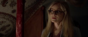 Movie still from “Suitable Flesh” (2023), directed by Joe Lynch – A woman wearing glasses and a white jacket; Close Up shot, Over the shoulder angle