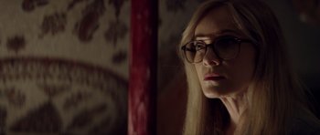 Movie still from “Suitable Flesh” (2023), directed by Joe Lynch – A woman wearing glasses and looking at the camera; Close Up shot, Over the shoulder angle