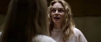 Movie still from “Suitable Flesh” (2023), directed by Joe Lynch – A woman with long blonde hair talking to another woman; Close Up shot, Over the shoulder angle