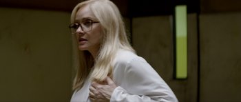 Movie still from “Suitable Flesh” (2023), directed by Joe Lynch – A woman in glasses and a white shirt; Close Up shot, Over the shoulder angle