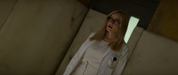 Movie still from “Suitable Flesh” (2023), directed by Joe Lynch – A woman wearing glasses and a white jacket; Medium shot, Low angle