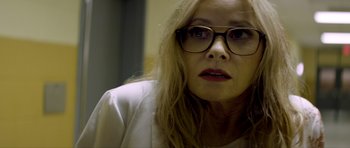 Movie still from “Suitable Flesh” (2023), directed by Joe Lynch – A person wearing glasses and a white shirt; Close Up shot, Over the shoulder angle