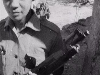 Movie still from “Summer of Soul (...Or, When the Revolution Could Not Be Televised)” (2021), directed by Questlove – An old black and white photo of a man holding a gun; Extreme Close Up shot, High angle