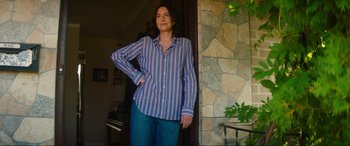 Movie still from “Summering” (2022), directed by James Ponsoldt – A woman standing in front of a stone wall; Medium shot, Low angle